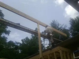 Carpenter setting a ridge beam over a new addition frame — Ice Dam Removal by Roofing Brothers in Olin